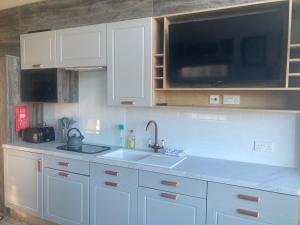 a kitchen with white cabinets and a sink and a microwave at Chapel Fields Holiday Park in Chapel Saint Leonards