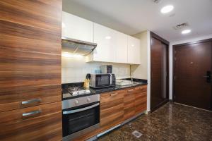 a kitchen with wooden cabinets and a stove top oven at KeyHost - Spacious Studio at Sparkle Tower Dubai Marina - K1280 in Dubai