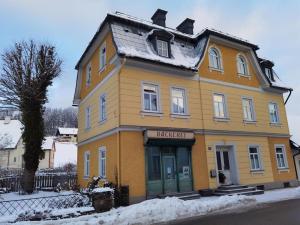 a yellow house on a street in the snow at Ferienwohnungen Weissenbacher in Mitterbach