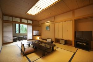 een woonkamer met een tafel en een televisie bij Hodakaso Yamano Hotel in Takayama
