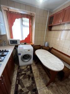 uma pequena cozinha com uma mesa e uma máquina de lavar roupa em Апартаменты рядом с парком центр em Vinnytsya