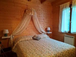 sypialnia z łóżkiem z baldachimem i dwoma oknami w obiekcie Apuan Sunset Apartment w mieście Careggine