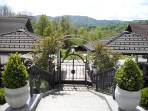 un cancello di ferro nero con due grandi piante in vaso di Vila Mirjam a Radovljica
