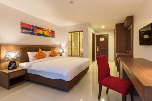 華欣的住宿－Riche Hua Hin Hotel - SHA Plus，一间卧室配有一张床、一张桌子和一把红色椅子