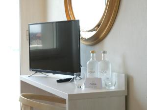 einen TV auf einem Tisch mit zwei Flaschen und Gläsern in der Unterkunft Hotel Imperial Beach - Dada Hotels in Rimini