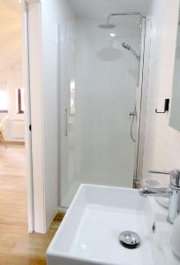 a white bathroom with a shower and a sink at Apartamentos la Garita - Casa Miro y Marianita - Cudillero in Cudillero