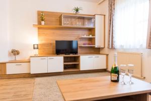 Almtalhotel Appartements in Pettenbach في Pettenbach: غرفة معيشة مع تلفزيون وطاولة مع كؤوس للنبيذ