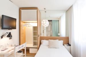 Schlafzimmer mit einem Bett, einem Schreibtisch und einem Spiegel in der Unterkunft Hotel Denit Barcelona in Barcelona