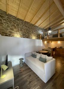 a living room with a white couch and a stone wall at acalma - sesmo in Sarzedas