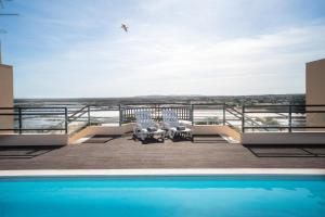- un balcon avec une piscine, des chaises et un oiseau dans l'établissement Sovipral Homes Casa Marina, à Olhão