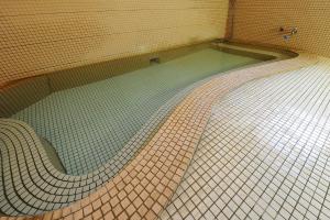 a swimming pool with a tiled floor in a bathroom at Dai Onsen Matsudaya Ryokan in Hanamaki