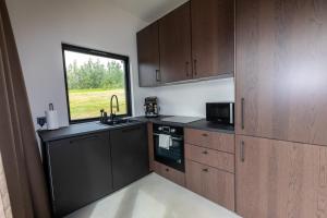 una cocina con armarios de madera y una ventana en North Mountain View Suites, en Akureyri