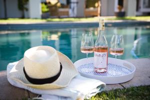 a hat and two glasses of wine next to a pool at Doran Vineyards in Paarl