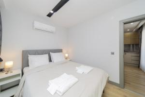 a white bedroom with a large bed with white pillows at Chic Flat with Central Location in Muratpasa in Antalya