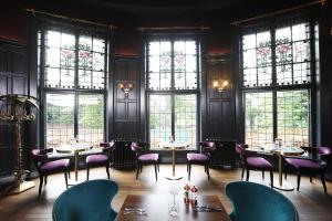 a restaurant with tables and chairs in a room with windows at Elmbank Hotel - Part of The Cairn Collection in York