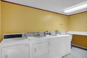eine Waschküche mit weißen Waschmaschinen und gelben Wänden in der Unterkunft Days-Inn by Wyndham Liverpool-Syracuse in Liverpool