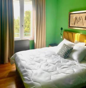 a large white bed in a green room with a window at St Nazaire Jardin des plantes superbe appartement in Saint-Nazaire