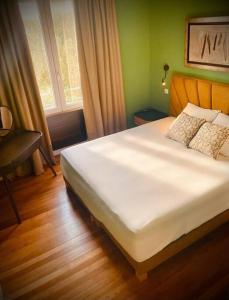 a bedroom with a white bed with a desk and a window at St Nazaire Jardin des plantes superbe appartement in Saint-Nazaire