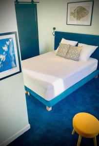 a bedroom with a bed and a yellow chair at St Nazaire Jardin des plantes superbe appartement in Saint-Nazaire