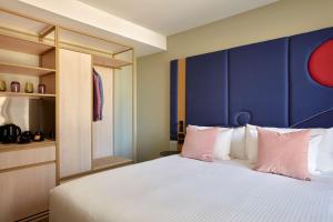 a bedroom with a large bed with a blue headboard at Quincy Hotel Melbourne in Melbourne