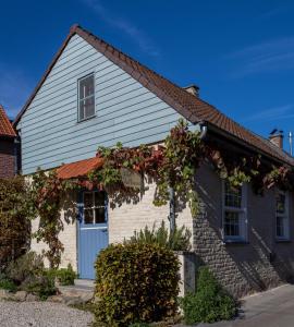 una casa blanca con una puerta azul y flores en Gîte les Mineurs, en Zottegem