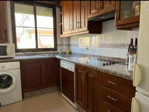 cocina con armarios de madera, lavadora y secadora en Apartamento Puente Romano con Parking gratuito, en Córdoba