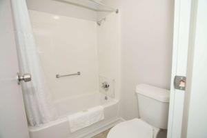 a white bathroom with a toilet and a shower at Travelodge by Wyndham Macon West in Macon