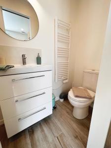 a white bathroom with a toilet and a mirror at Charmante Maisonnette au calme / Jardin privatif in Clermont