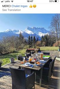 Chalet Ingas في Troistorrents: طاولة خشبية عليها كراسي وطعام مع جبال