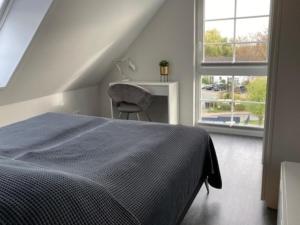 a bedroom with a bed and a chair and a window at Kabine 9 in Grömitz