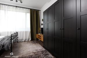 - une chambre avec des armoires noires, un lit et une fenêtre dans l'établissement Modern Condo near Morii Lake, à Bucarest