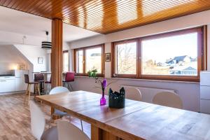 a dining room with a wooden table and some windows at Bödefeld in Schmallenberg