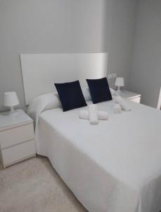 a white bed with blue pillows in a bedroom at Domus Deorum- a 200 m del Teatro Romano in Mérida