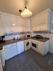 a kitchen with white cabinets and a washer and dryer at 117A - Elegante apartamento en pleno centro in Gijón