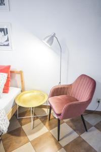 クラクフにあるLION apartments - Your own apartment in Cracowのリビングルーム(ピンクの椅子、テーブル付)