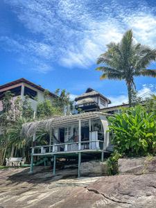 a house with a porch and a palm tree at Cabana Do Mar in Angra dos Reis