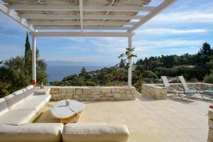 a patio with a white couch and a table at Apeiron II Villa by PaxosRetreats in Oziás