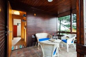 una veranda con tavolo, sedie e parete in legno di La Baita del Convento - Il tuo rifugio sull'Etna a Nicolosi