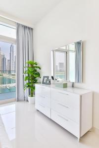 een witte woonkamer met een witte dressoir en een spiegel bij Ultra Luxury Emaar Beachfront - Private Beach and Pool in Dubai