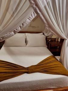 Una cama con dosel con una cinta marrón. en Bangalô alto do Mucugê, en Arraial d'Ajuda