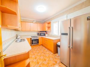 a kitchen with wooden cabinets and a stainless steel refrigerator at Cubo's Sporting Villa Paloma in Villafranco de Guadalhorce