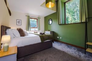 a bedroom with green walls and a bed with a window at Finest Retreats - Idris Barn Helm y Llwyn Barn in Dolgellau