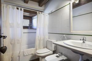 a white bathroom with a toilet and a sink at Luderna - Casa Sendrosa in Gessa
