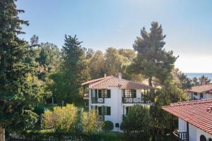 ein weißes Haus mit Bäumen im Hintergrund in der Unterkunft Beach Front Vintage Villa Kalliktratis in Nea Kallikratia