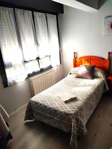 Schlafzimmer mit einem Bett mit einem Kopfteil aus Holz und Fenstern in der Unterkunft PENSIÓN PESQUERO in Burgos