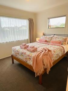 a bedroom with a bed with pink towels on it at Aintree On The Park in Mount Maunganui