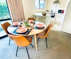 a dining room table with chairs and a kitchen at Aintree On The Park in Mount Maunganui