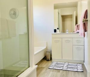 a bathroom with a shower and a sink and a mirror at Aintree On The Park in Mount Maunganui