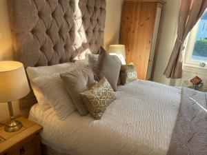 una camera da letto con un letto bianco e cuscini sopra di Beechwood Ensuite Guest House ad Ayr