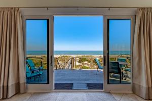 a room with doors open to a balcony with the ocean at Fletcher Family Friendly Home in Fernandina Beach